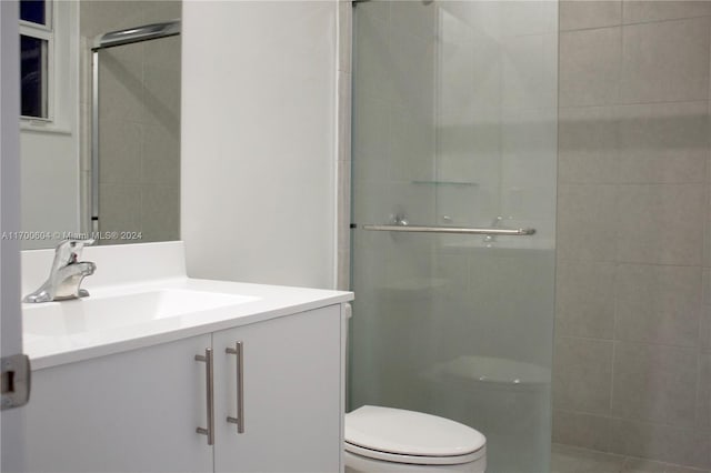 bathroom featuring tile patterned flooring, vanity, toilet, and walk in shower