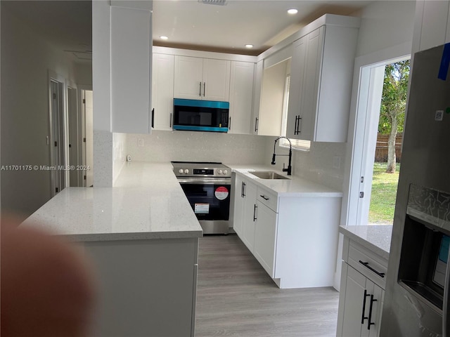 kitchen featuring sink, white cabinetry, stainless steel appliances, and light wood-type flooring