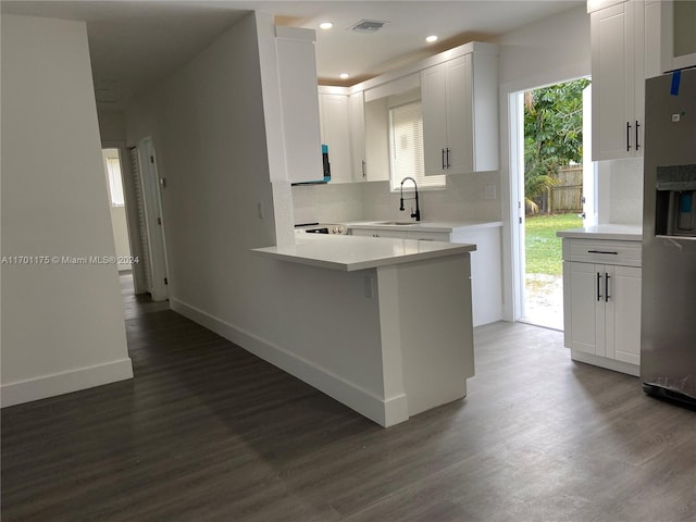 kitchen featuring kitchen peninsula, stainless steel fridge, white cabinets, and dark hardwood / wood-style floors