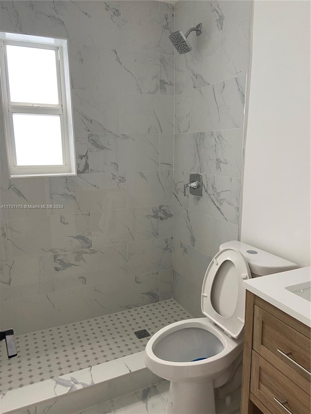 bathroom featuring tiled shower, vanity, and toilet