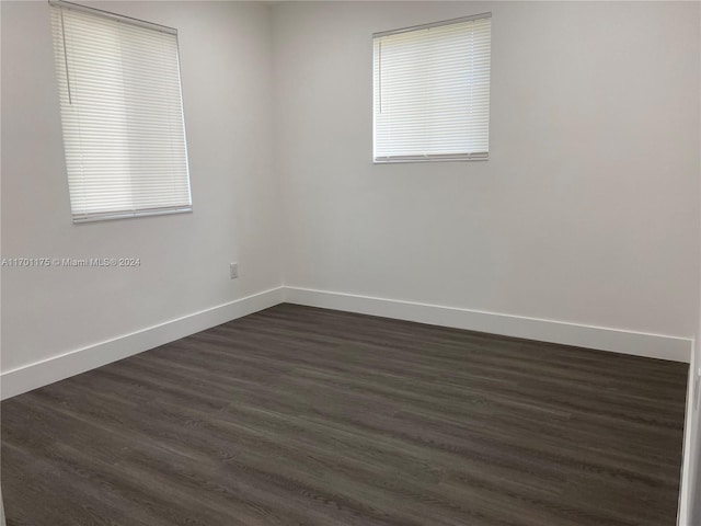 empty room with a healthy amount of sunlight and dark wood-type flooring