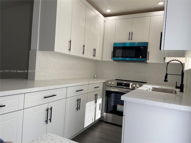 kitchen with dark wood-type flooring, sink, light stone counters, white cabinetry, and stainless steel appliances