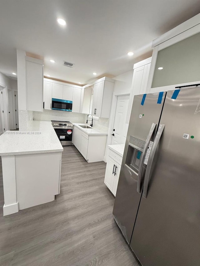 kitchen featuring white cabinetry, sink, stainless steel appliances, light stone counters, and light hardwood / wood-style floors