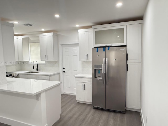 kitchen with sink, light hardwood / wood-style flooring, decorative backsplash, appliances with stainless steel finishes, and white cabinetry