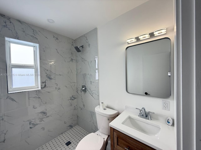 bathroom featuring a tile shower, vanity, and toilet