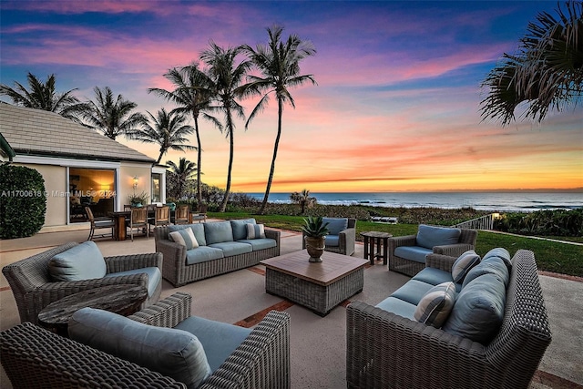 patio terrace at dusk with outdoor lounge area and a water view