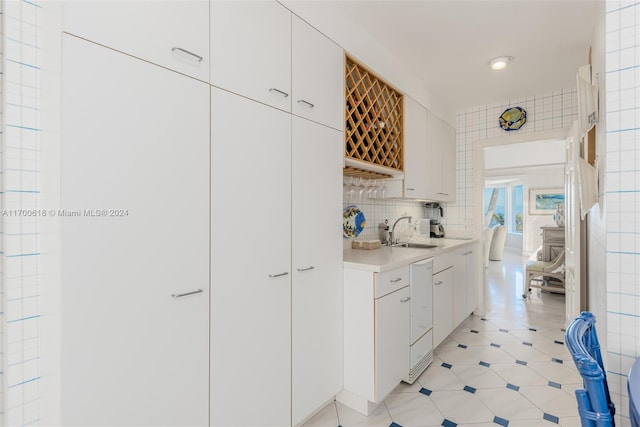 kitchen featuring decorative backsplash, white cabinetry, sink, and dishwasher