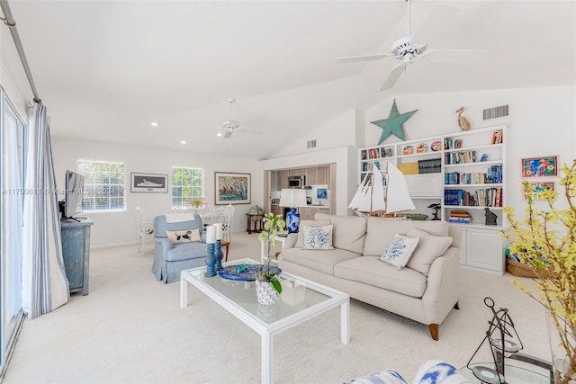 carpeted living room with ceiling fan and vaulted ceiling