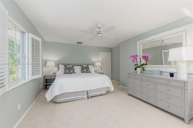 bedroom with multiple windows, ceiling fan, and light colored carpet