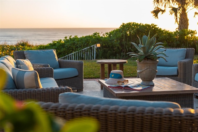 patio terrace at dusk featuring an outdoor living space and a water view