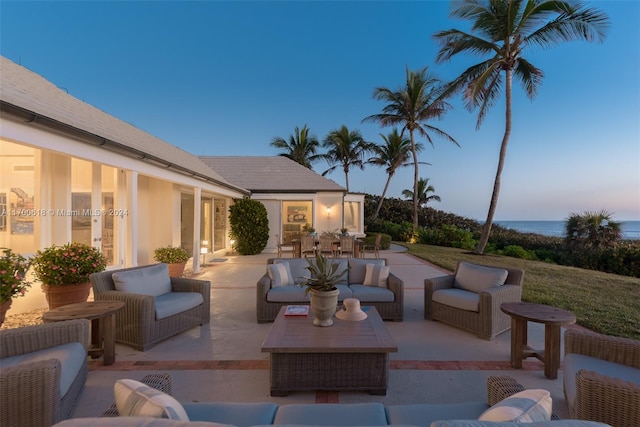 patio terrace at dusk featuring outdoor lounge area and a water view