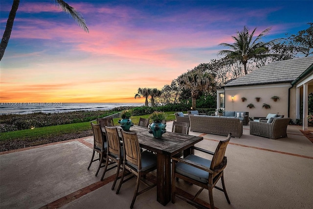 patio terrace at dusk with outdoor lounge area and a water view