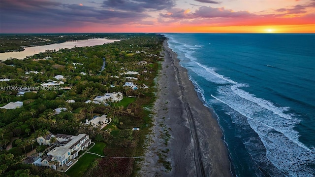 aerial view at dusk with a view of the beach and a water view