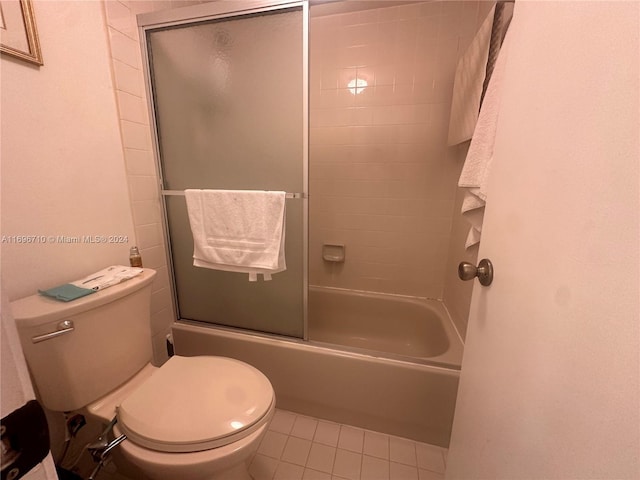 bathroom featuring combined bath / shower with glass door, tile patterned flooring, and toilet