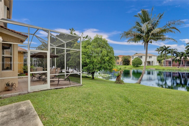 view of yard with a water view, glass enclosure, and a patio area