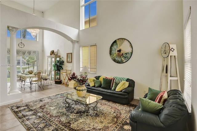 living room featuring light tile patterned floors, a towering ceiling, and decorative columns