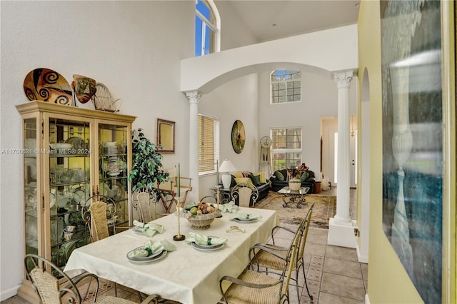 tiled dining room featuring decorative columns and a towering ceiling