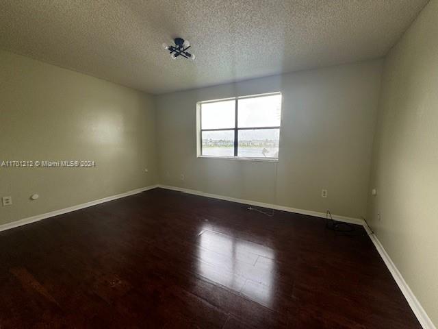 unfurnished room featuring a textured ceiling and dark hardwood / wood-style floors