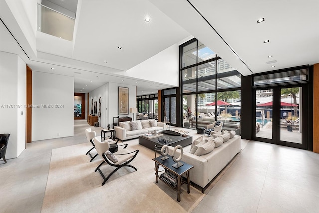 living room with a high ceiling and a wall of windows