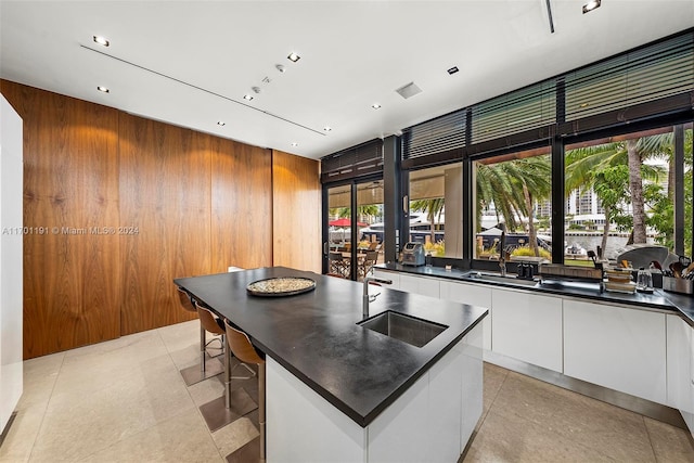 kitchen with a wealth of natural light, a center island, white cabinets, and wooden walls