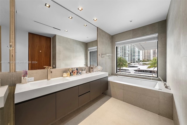 bathroom featuring tile patterned floors, tiled bath, vanity, and tile walls