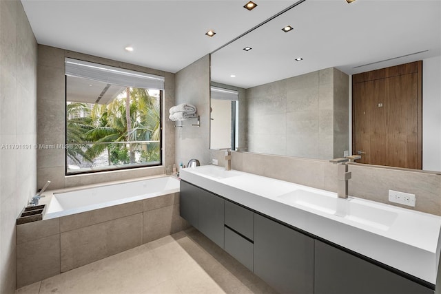 bathroom featuring tile patterned flooring, vanity, a relaxing tiled tub, and tile walls