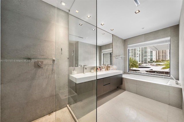 bathroom with tile patterned floors, vanity, shower with separate bathtub, and tile walls