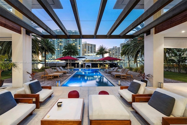 pool at dusk featuring a pergola, a patio area, and an outdoor hangout area