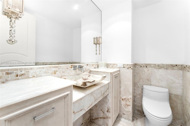 bathroom with vanity, tile walls, and toilet