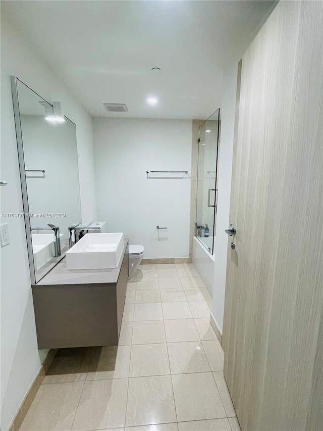 full bathroom with tile patterned flooring, vanity, bath / shower combo with glass door, and toilet