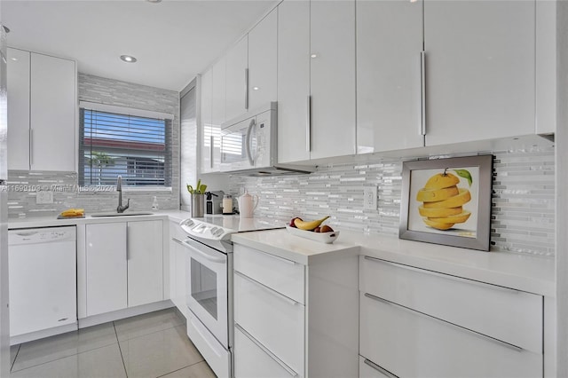 kitchen with tasteful backsplash, white cabinetry, sink, and white appliances