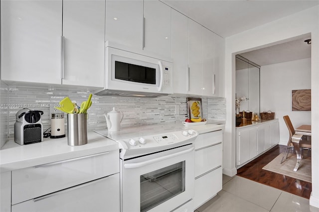 kitchen featuring white cabinets, light wood-type flooring, white appliances, and tasteful backsplash