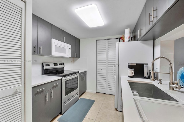 kitchen featuring light tile patterned floors, white appliances, tasteful backsplash, and sink