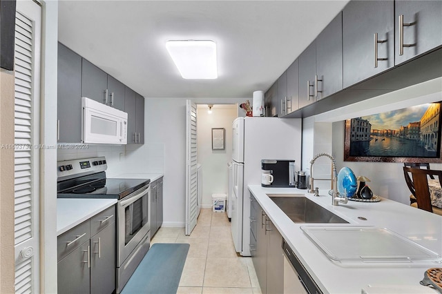 kitchen featuring tasteful backsplash, sink, light tile patterned floors, and white appliances