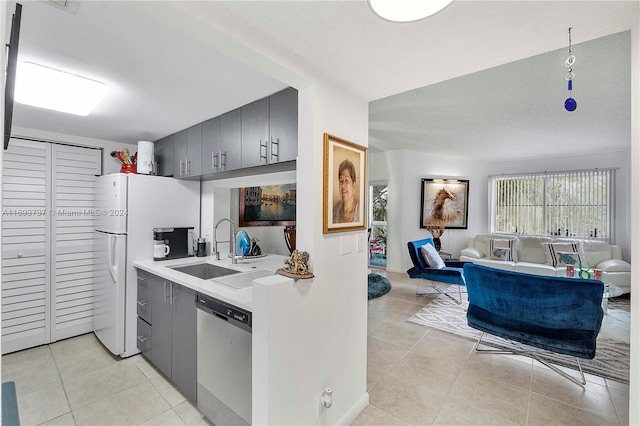 kitchen featuring dishwasher, white fridge, light tile patterned flooring, and sink