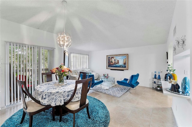 dining room featuring light tile patterned floors, a textured ceiling, and an inviting chandelier