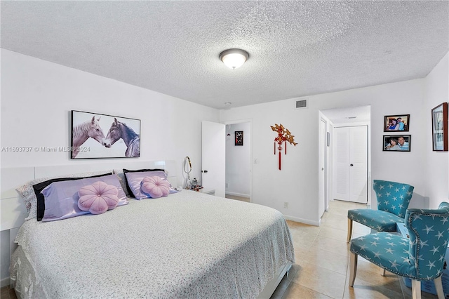 bedroom with light tile patterned floors and a textured ceiling