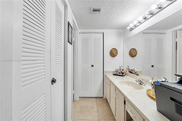 bathroom featuring tile patterned flooring, vanity, and a textured ceiling