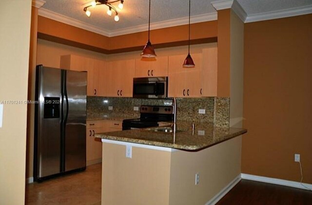 kitchen featuring pendant lighting, crown molding, appliances with stainless steel finishes, stone countertops, and kitchen peninsula