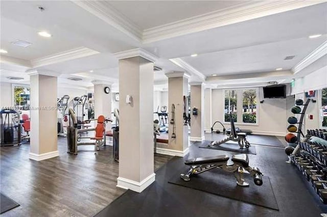 exercise room with a tray ceiling, crown molding, decorative columns, and dark wood-type flooring