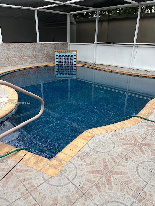 view of swimming pool featuring glass enclosure