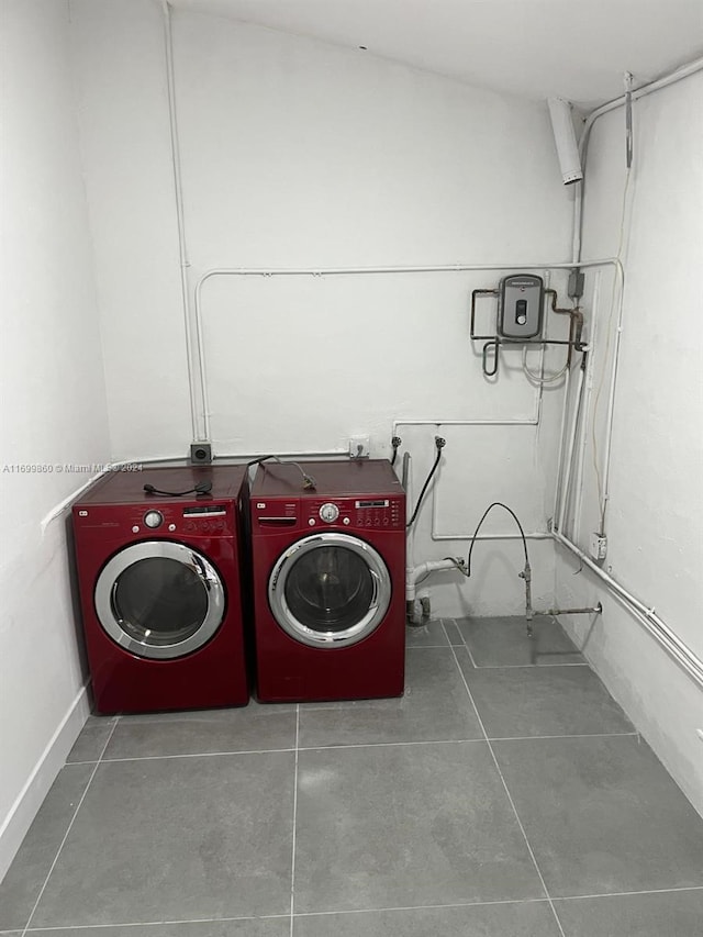 clothes washing area with dark tile patterned floors and washer and dryer