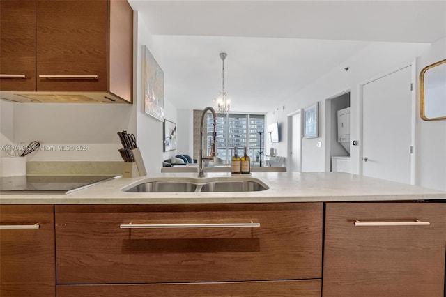 kitchen featuring black electric cooktop, sink, exhaust hood, and decorative light fixtures