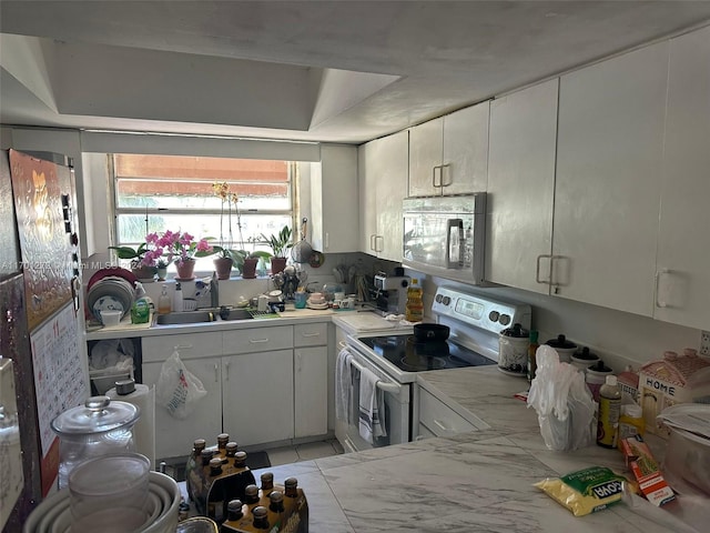 kitchen with white electric range oven, white cabinetry, and sink