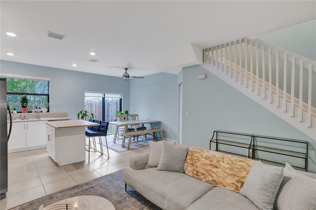 living area with light tile patterned flooring, recessed lighting, a ceiling fan, visible vents, and stairs