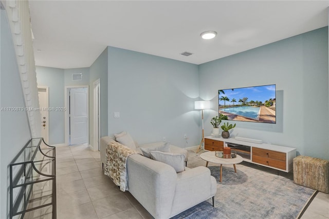 living room featuring light tile patterned floors, visible vents, and baseboards