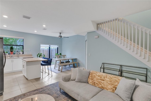 living room featuring ceiling fan, sink, and light tile patterned floors