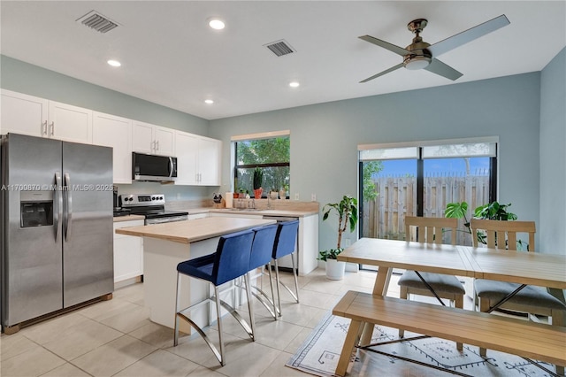 887 NE 211th St Unit 887, Miami, FL 33179 - kitchen with visible vents, white cabinets, appliances with stainless steel finishes, a center island, and light countertops