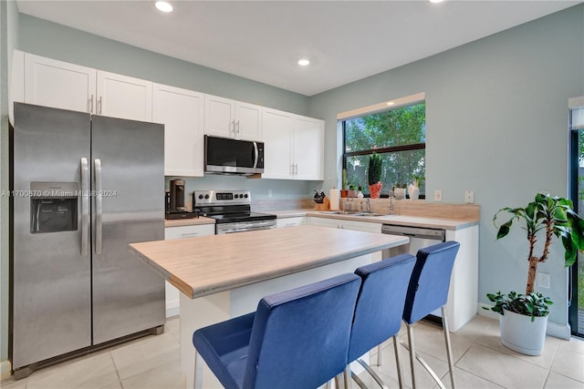 kitchen featuring white cabinets, light tile patterned floors, sink, and appliances with stainless steel finishes