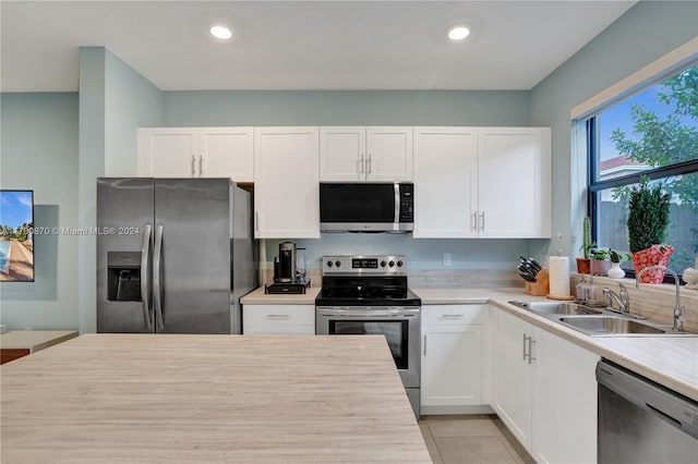 kitchen featuring light tile patterned flooring, white cabinetry, sink, and appliances with stainless steel finishes